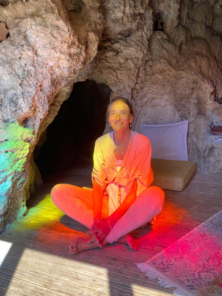 Photo of Githa Ben-David sitting in rainbow coloured light. Click image to book the series of 10 online sound scanning sessions.